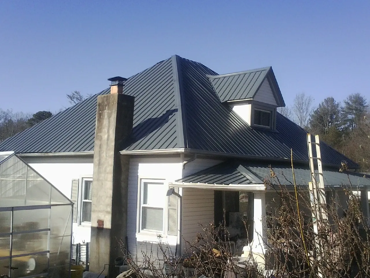 Dark blue standing seam metal roof on a white farmhouse with dormer — Slate & Tile Roof Repair by Roofing Brothers in New Trenton