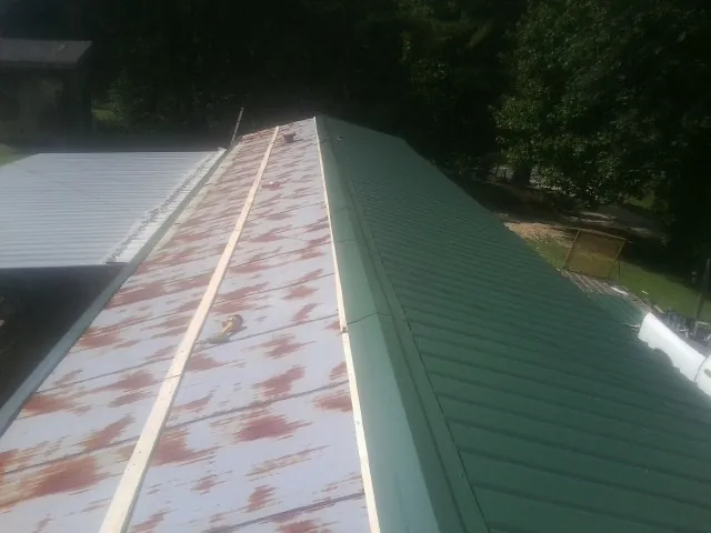 Old rusted panels beside newly installed green metal roofing — Wind Damage Roof Repair by Roofing Brothers in New Trenton