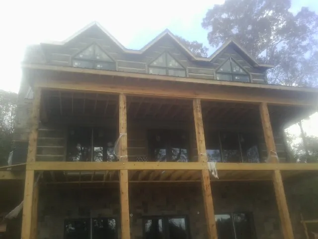 Dormers and porch framing on a large log home under construction — Roof Coating work by our crew in New Trenton