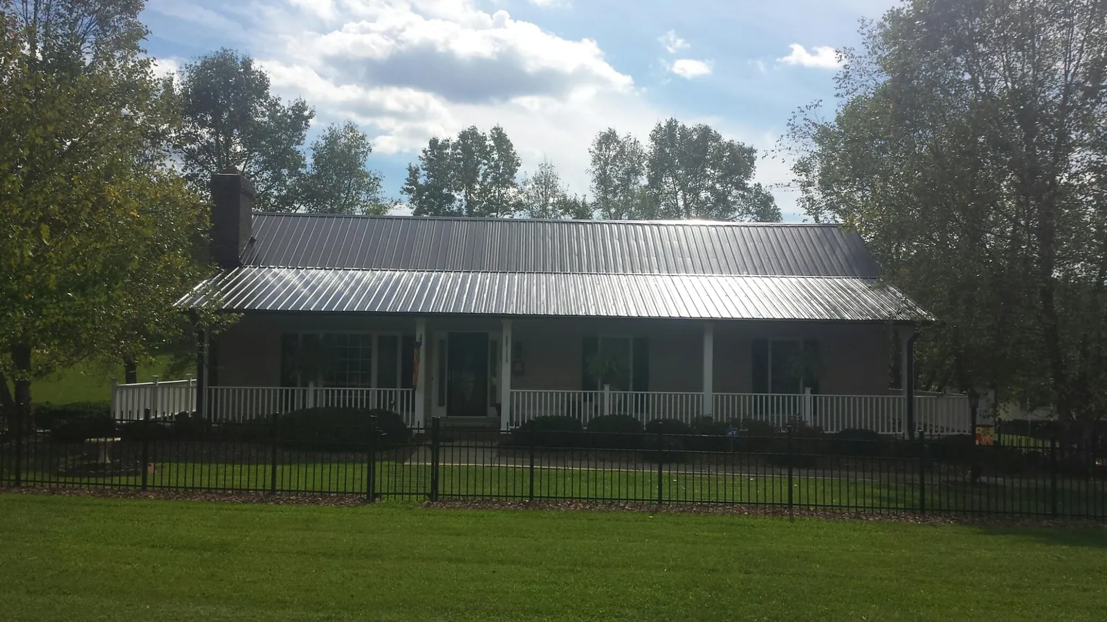 Gray metal roof on a brick ranch with a full width front porch — Gutter Guard Installation work by our crew in New Trenton