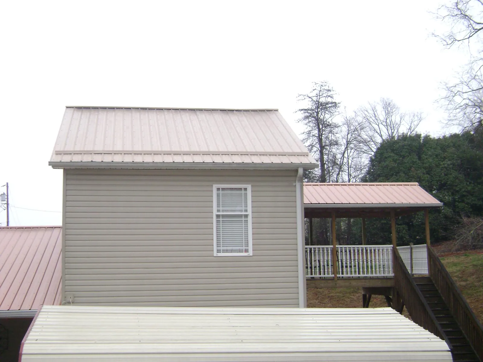 Tan metal roofs on a two story addition and attached porch, from a Roof Replacement job in New Trenton